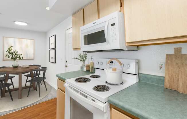 a kitchen with green countertops and a white stove top oven with a white microwave above it