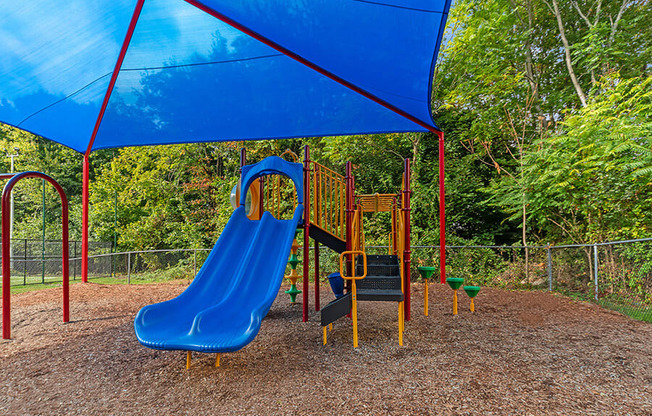 Community Playground with Slide and Blue Canopy at Heights at Marlborough Apartments located in Marlborough, MA.