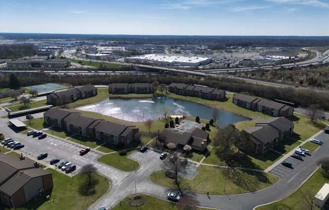 an aerial view of a pond in the middle of a neighborhood with houses and cars