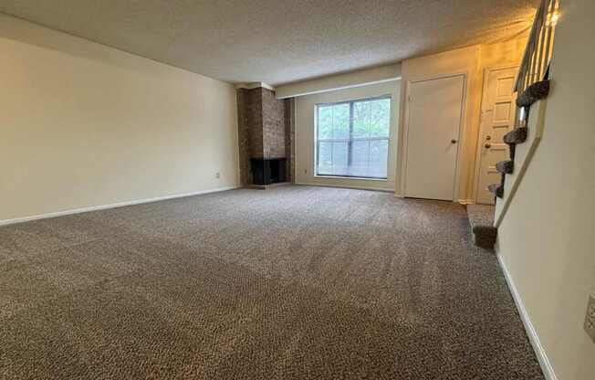 A carpeted room with a staircase on the right side.
