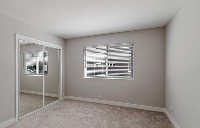A room with a carpeted floor and a window with blinds.