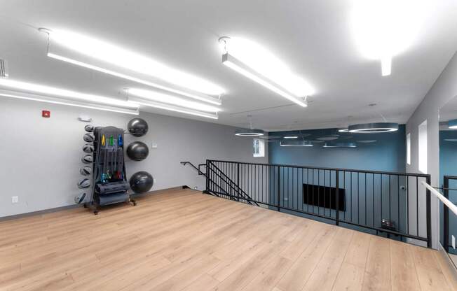 A gym with a wooden floor, a railing, and exercise equipment.