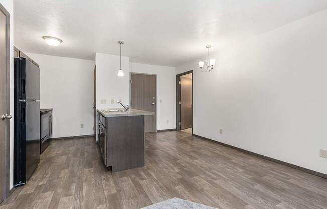 A kitchen with a refrigerator, sink, and cabinets.