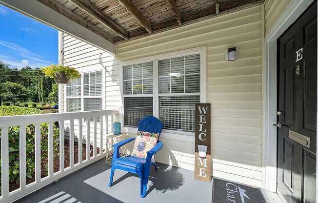 A blue chair sits on a porch with a sign that says "Welcome".