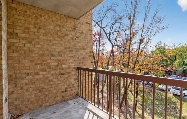A balcony with a brick wall and a metal railing.