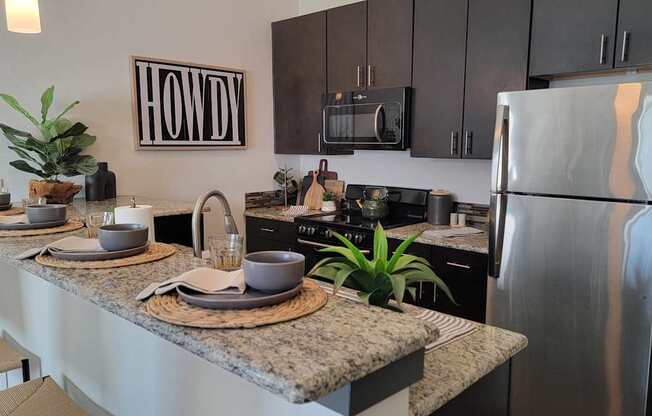 A modern kitchen with a granite countertop and stainless steel appliances.