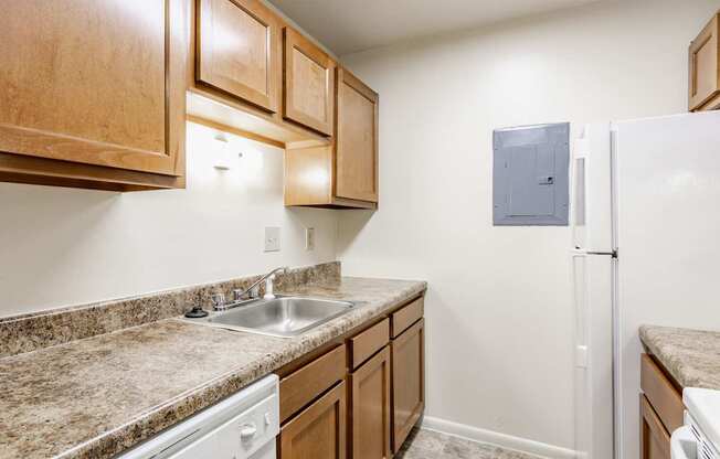 A kitchen with a white fridge and brown cabinets