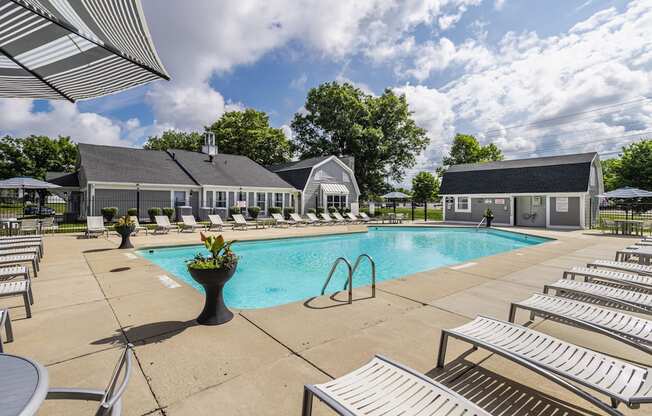 A pool area with sun loungers and a building in the background