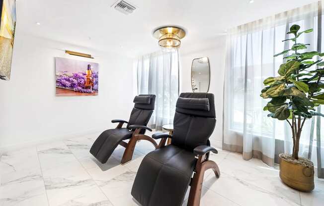 a spa room with three black massage chairs and a potted plant