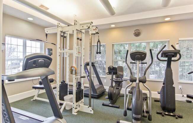 a gym with cardio machines and weights at the enclave apartments