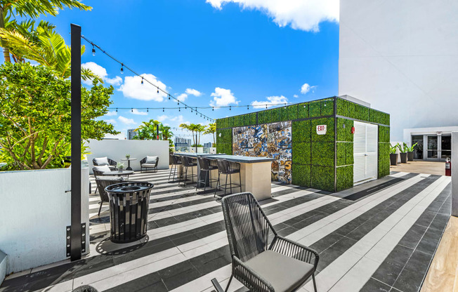 a patio with chairs and tables and a green wall with mosaics on it