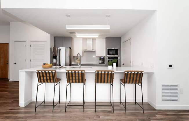 A modern kitchen with a white island and bar stools.
