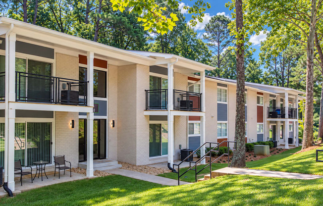 Apartment buildings with black balcony railings and patios beside a sloping courtyard at Icon Avondale Apartments in Decatur, GA.