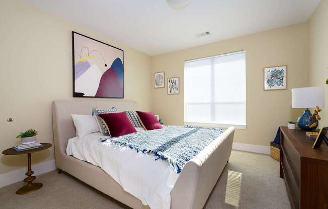 A bedroom with a bed, a nightstand, and a painting on the wall.