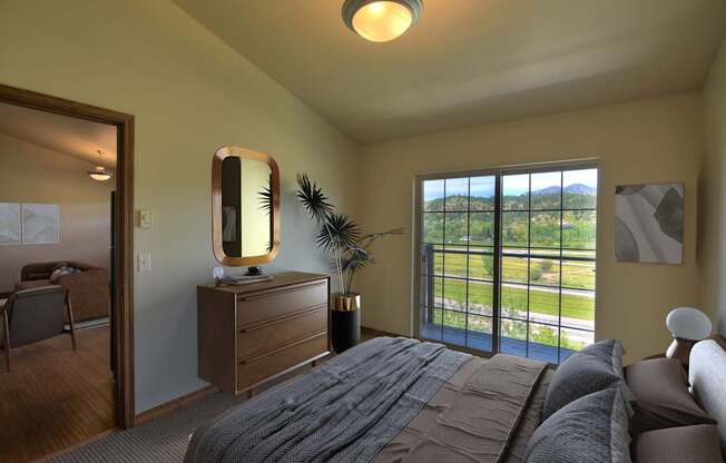 A bedroom with a large bed and a view of the outdoors through the window.