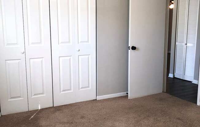 an empty living room with white doors and a carpeted floor