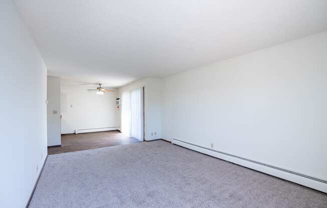 a living room with white walls and carpet and a ceiling fan. Eagan, MN Glen Pond Apartments