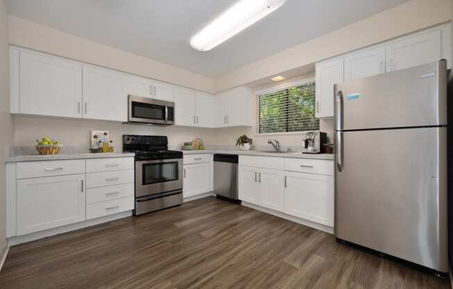 a kitchen with white cabinets and stainless steel appliances in the townhome floorplan