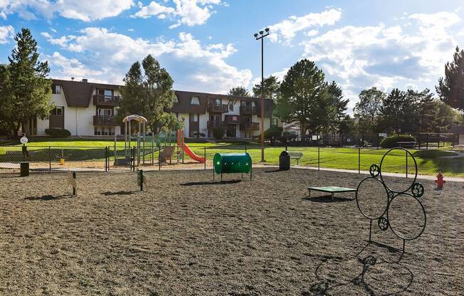 A playground with a sandy area and a swing set.