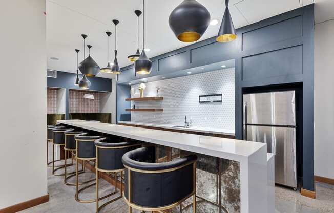 a large kitchen with a long counter top and a row of bar chairs