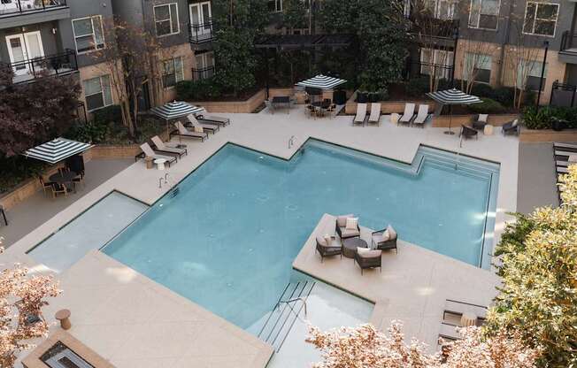A large outdoor swimming pool surrounded by lounge chairs and umbrellas.