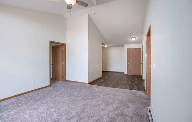 A room with a grey carpet and wooden doors. Bismarck, ND Sierra Ridge Apartments