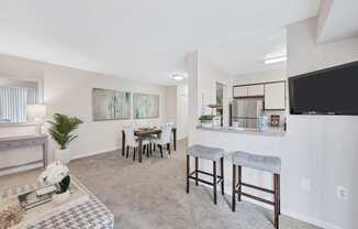 a living room with a dining area and a kitchen in the background