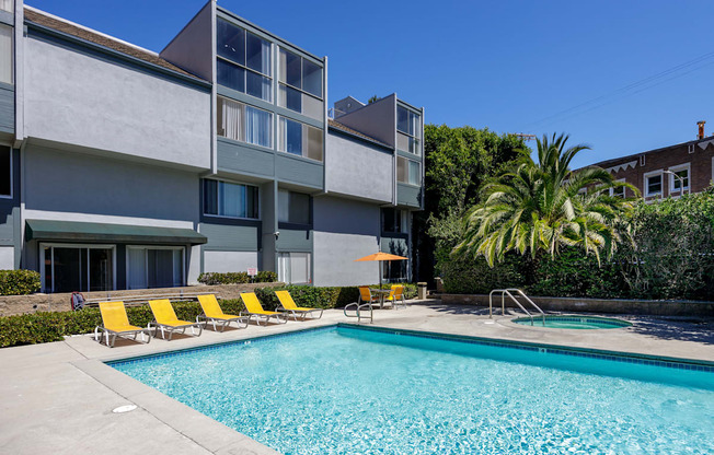 a swimming pool with yellow chairs in front of a building