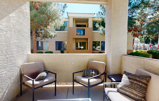 a patio with two chairs and a table in front of a building