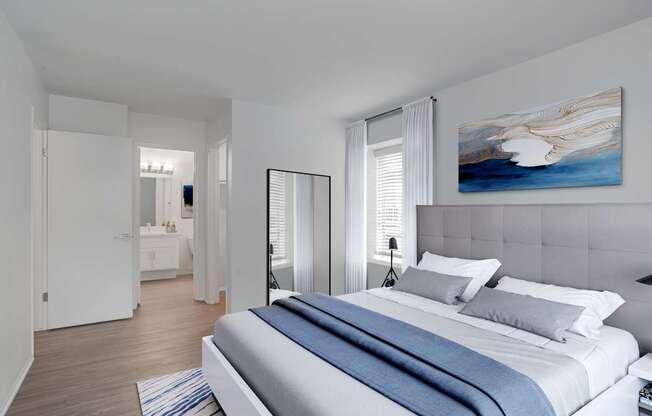 A bedroom with a large bed and a painting on the wall.