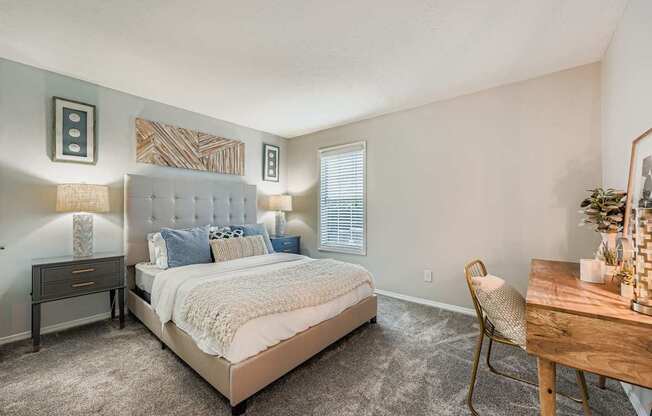 A bedroom with a large bed, a chair, and a table.