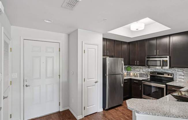 A kitchen with a refrigerator, oven, and microwave.