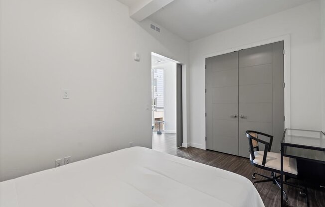 A white bed in a room with a chair and a table.