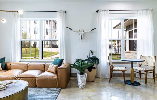 Living room with a leather couch and a table and windows at The Parker Austin, Pflugerville, Texas