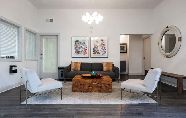 a living room with a black couch and two white chairs at The Summit Apartments, Memphis, 38128