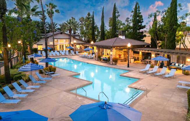 A large outdoor swimming pool surrounded by lounge chairs and umbrellas.