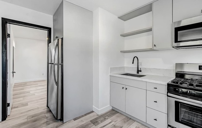 A modern kitchen with white cabinets and a stainless steel refrigerator.