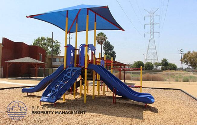 a playground with two slides and a umbrella