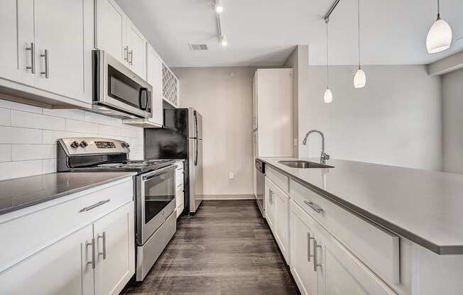 an empty kitchen with white cabinets and stainless steel appliances