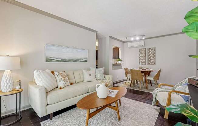 A living room with a white couch and a painting on the wall.