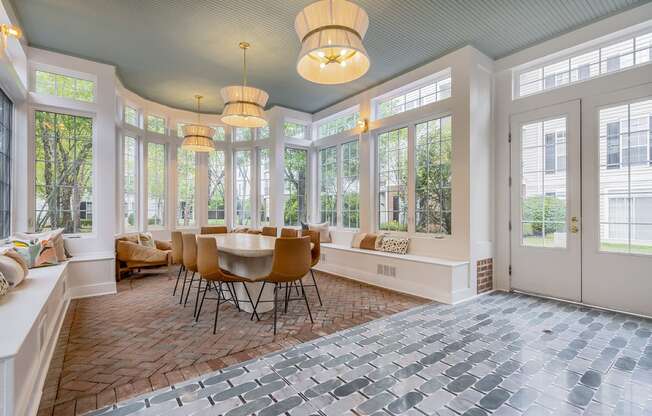 a sun room with a table and chairs and large windows