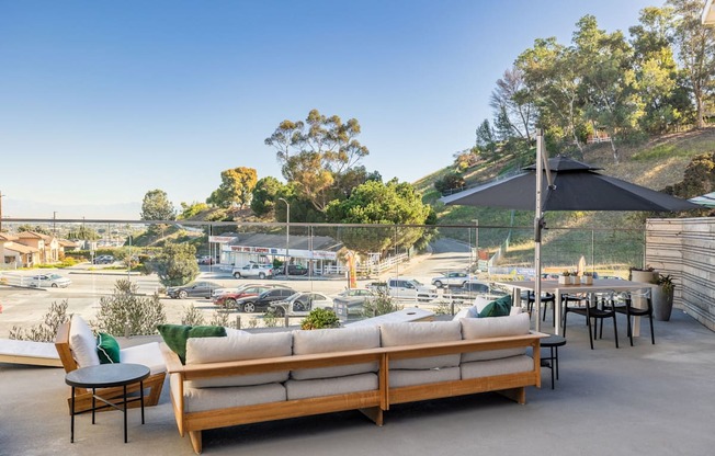 a rooftop patio with couches and tables and an umbrella