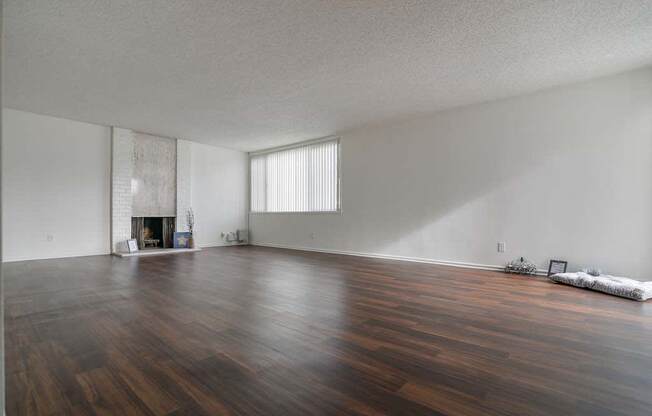 an empty living room with a fireplace and hardwood floors at Park Avenue Apartments, Long Beach, CA