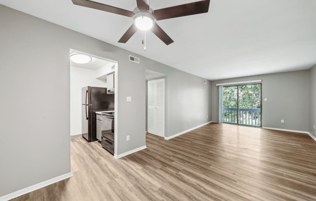 an empty living room with a ceiling fan and a window