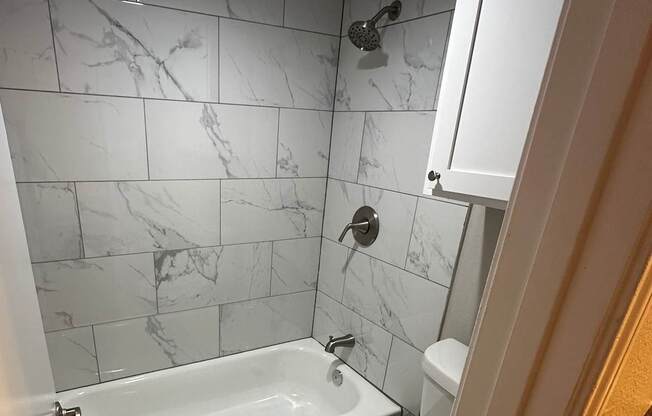 A bathroom with a marble tile floor and a white toilet.
