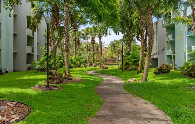 a path through the grass and trees in front of an apartment building