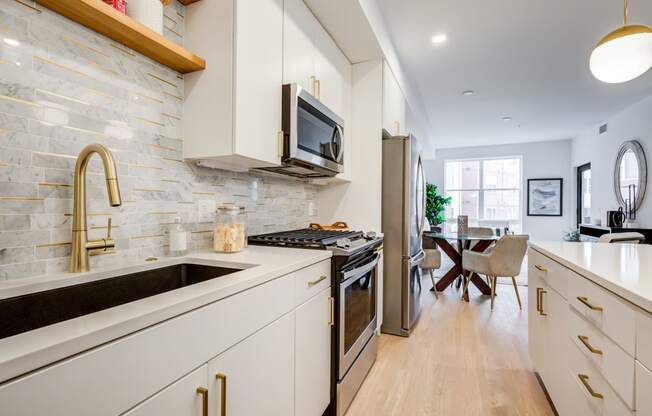 a kitchen with white cabinets and stainless steel appliances and a sink at Rialto, District of Columbia