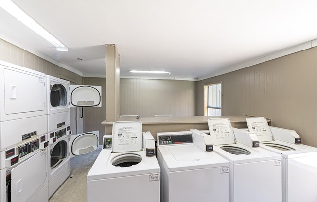 A row of white front load washing machines in a laundromat.