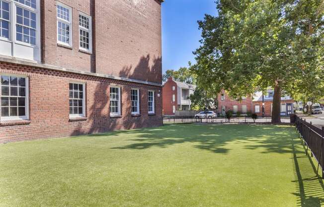 the yard of a brick building with green grass and a tree