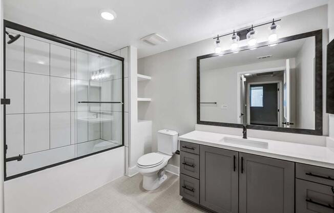 a bathroom with a toilet sink mirror and shower at The Vineyards Apartments, Porter Ranch, CA, 91326